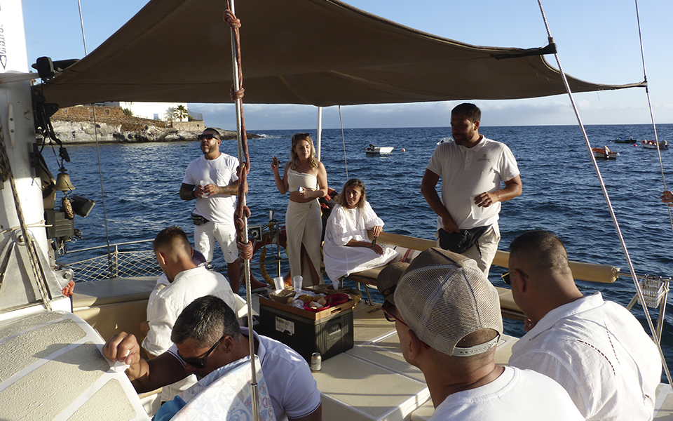 Ocho personas en la popa de un catamarán en Tenerife disfrutando de catering y bebidas durante una tarde soleada de verano