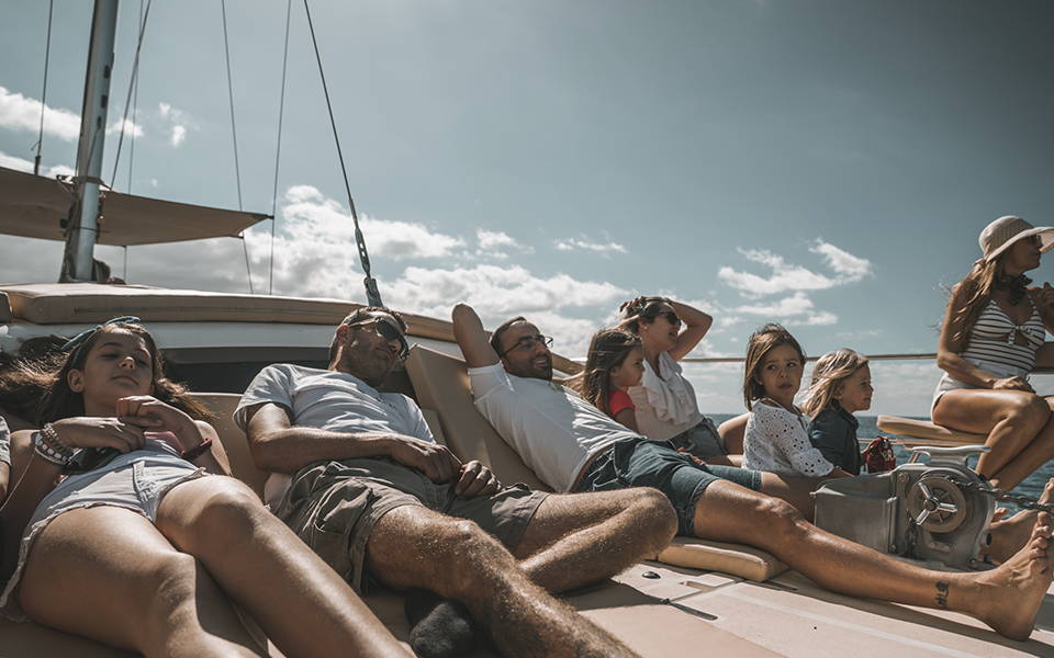 Adultos y niños tumbados en las colchonetas de un catamarán en Tenerife tomando el sol durante una excursión en el mar